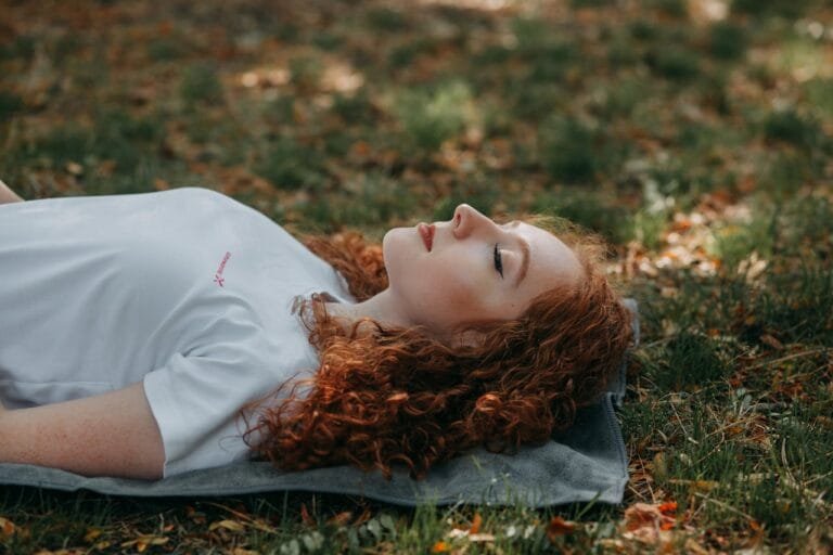 Woman relaxing on an acupressure mat outdoors in the park